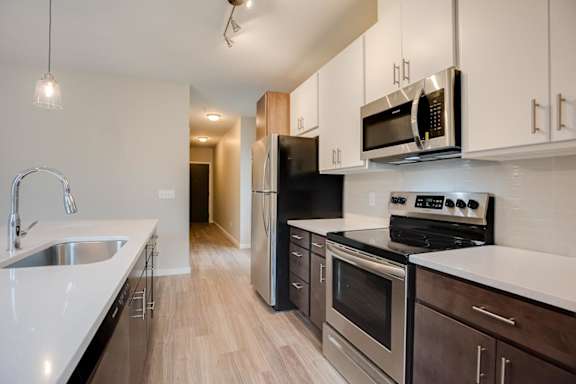 A kitchen with an oven, microwave, and island with a sink