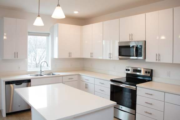 A spacious kitchen with white cabinets and stainless steel appliances.