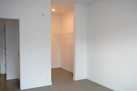 A white room with a doorway leading to another an empty walk-in closet
