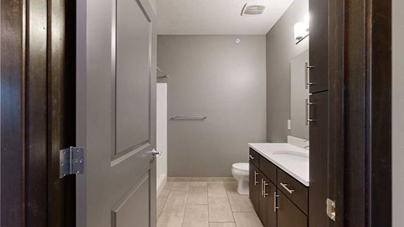 a bathroom with a granite vanity sink and a walk-in shower