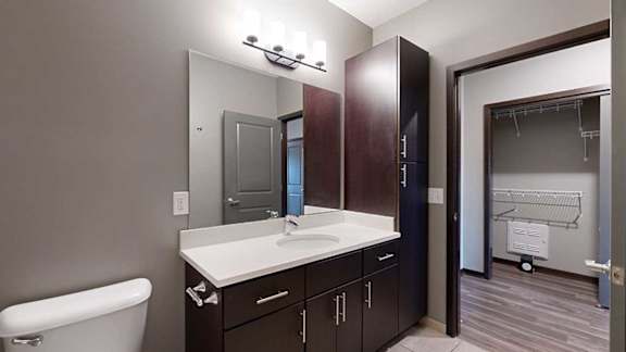 a bathroom with a white granite countertop and dark brown cabinets