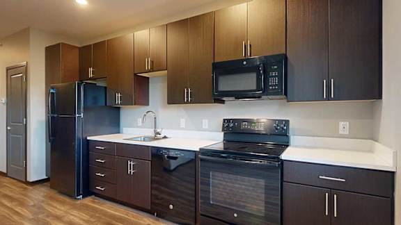 a kitchen with dark wood cabinets, white granite countertops, and black appliances