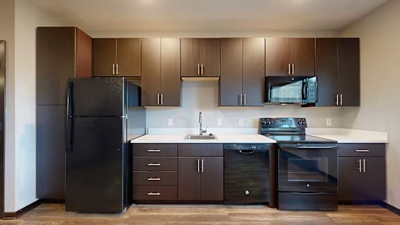 a kitchen with dark brown cabinets, white granite countertops, and black appliances
