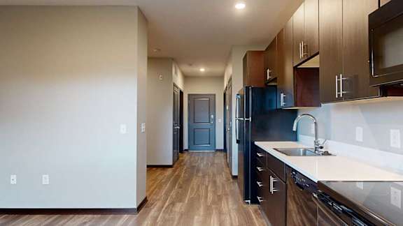 a hallway that connects the entrance to the bathroom, the sleeping area, the kitchen, and the living area