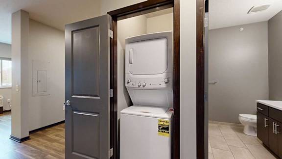 a laundry closet with a stackable full sized washer and dryer