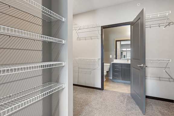 Walk-in closet with extensive wire shelving and carpeted flooring, providing direct access to an adjoining bathroom.