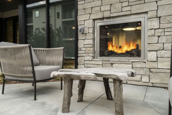 Outdoor stone firepit with a table and chair next to it