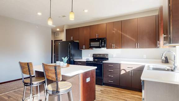a kitchen with dark brown wooden cabinets and a bar with two chairs