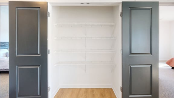 A coat closet with double doors and white wire shelving