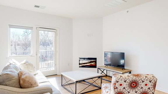 A living room with a couch, a coffee table, fireplace, and a television.
