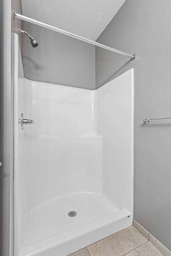 Apartment bathroom with a walk-in shower, neutral finishes, and a shower curtain rod.