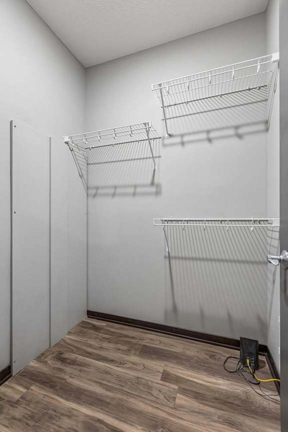 Walk-in apartment closet with wood-style flooring and built-in wire shelving for organized storage.