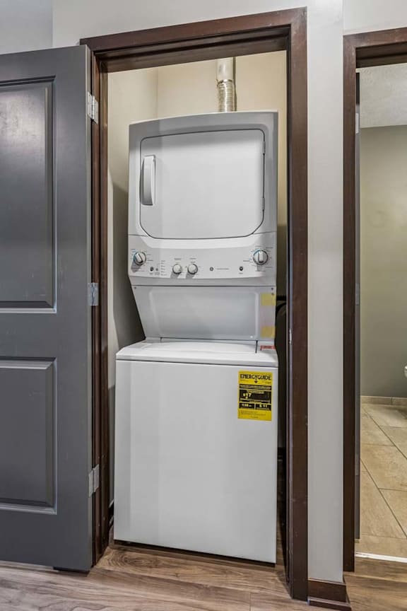 In-home apartment laundry closet with a stacked washer and dryer, conveniently tucked behind bi-fold doors.