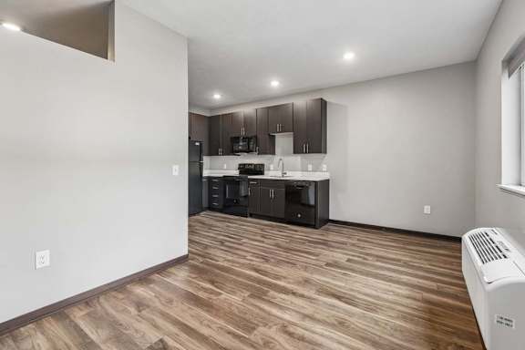 Open studio apartment with wood-style flooring, a compact kitchen, recessed lighting, and a bright, open living area.