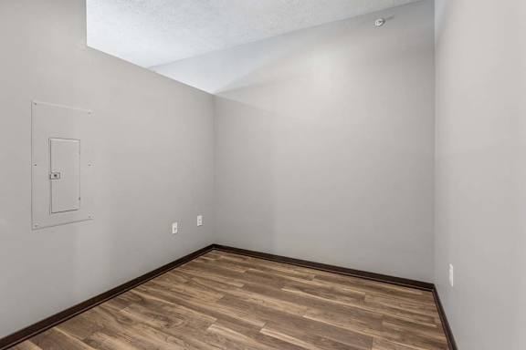 Flexible studio apartment nook with wood-style flooring, neutral walls, and an open layout for added living or workspace.