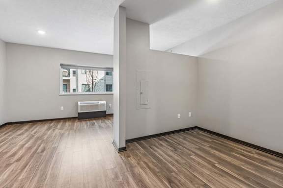 Studio apartment with a flexible alcove, wood-style flooring, and an open layout leading to the bright living area.