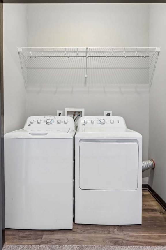 Dedicated apartment laundry closet with a side-by-side washer and dryer and built-in wire shelving.