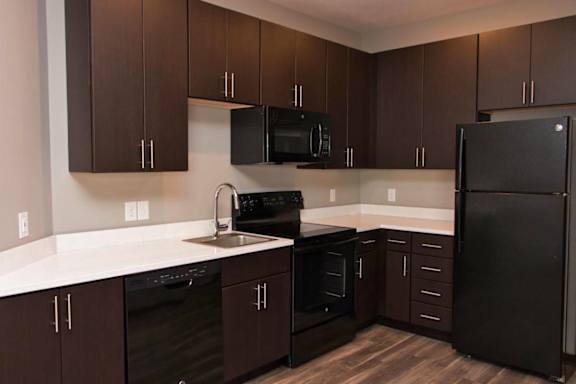 A kitchen with brown cabinets and black appliances.