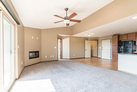 A spacious living room with a fireplace and a ceiling fan.