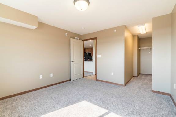 A spacious room with a carpeted floor and a doorway leading to another room.