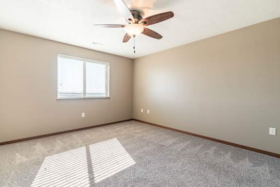 A room with a ceiling fan and a window.