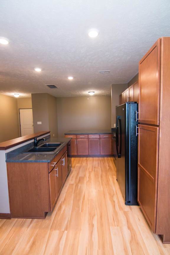 A kitchen with wooden cabinets and a black refrigerator.