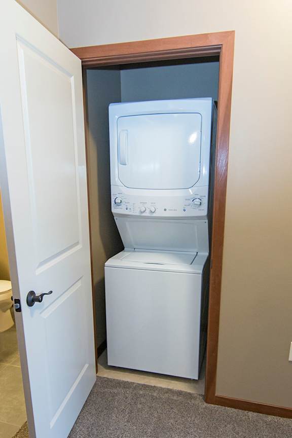 A white washing stacked washer and dryer is in a small closet.