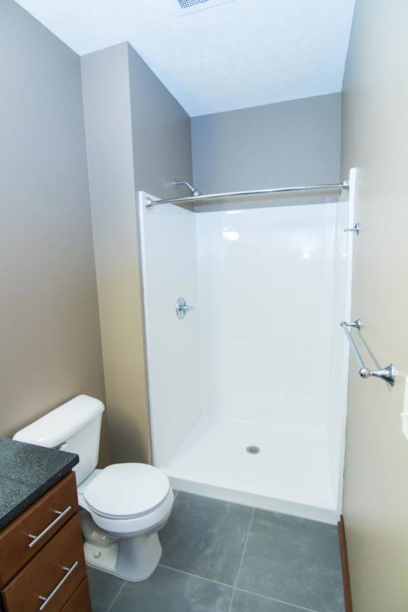 A white toilet sits next to a walk-in shower.