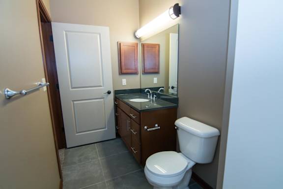 A bathroom with a toilet, sink, and mirror.