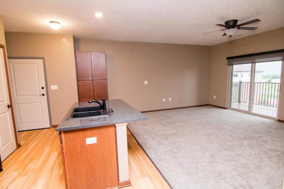 A kitchen with an island, open to a large living room