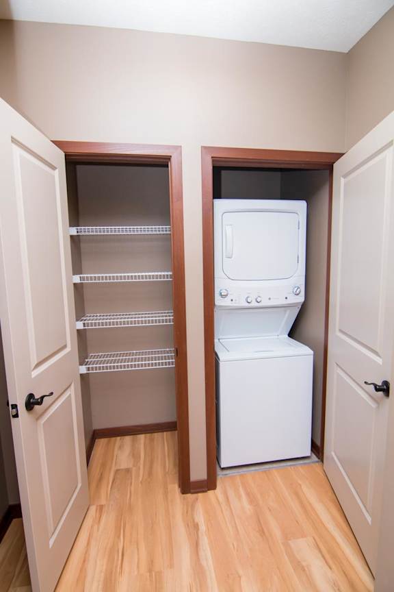 A stacked washer and dryer in a closet with another linen closet next to it