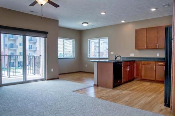 A spacious kitchen and living room with wooden floors and a ceiling fan.