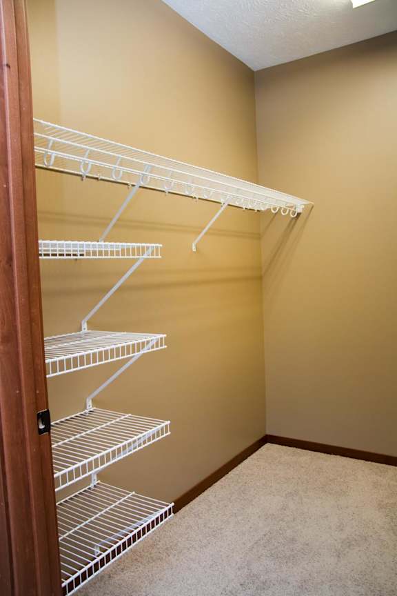 Empty white wire shelves in large walk-in closet
