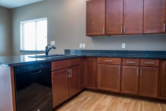 A kitchen with brown cabinets and a black countertop.