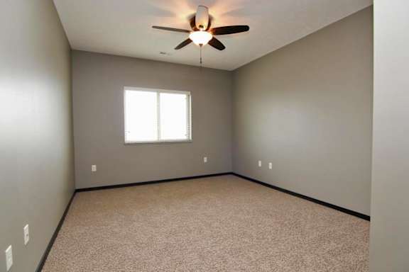 A room with a ceiling fan and a window.