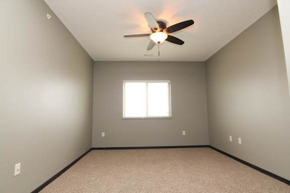 A room with a ceiling fan and a window.