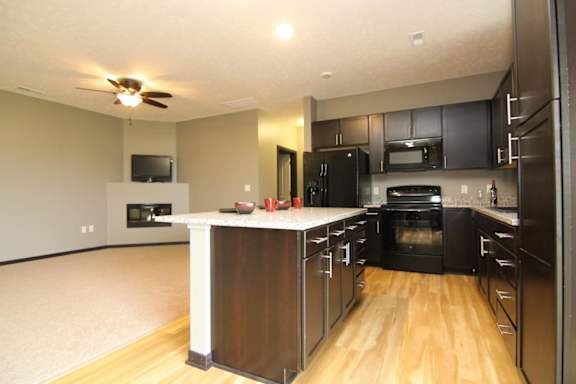 A kitchen with black appliances and wooden floors.