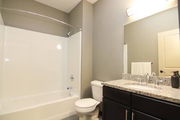A bathroom with a white toilet and a white bathtub.