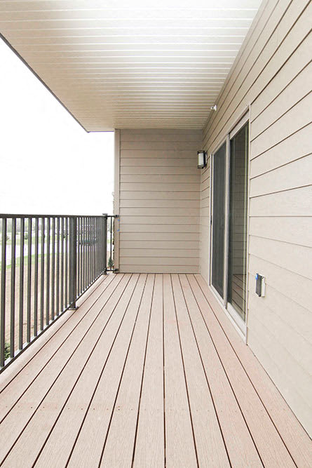 A wooden deck with a metal railing and a sliding glass door.