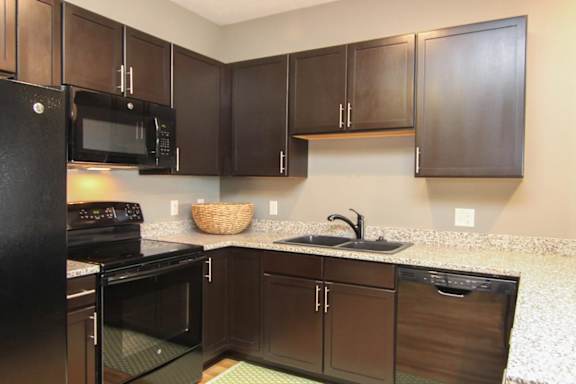 A kitchen with black appliances and brown cabinets.