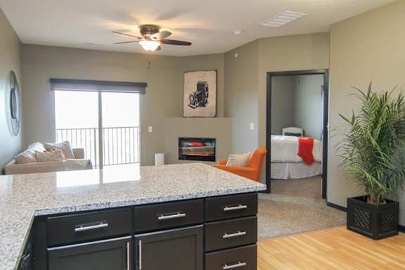 A room with a ceiling fan and a bed in the background.