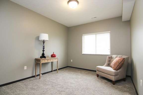 A room with a table, a lamp, a chair and a window.