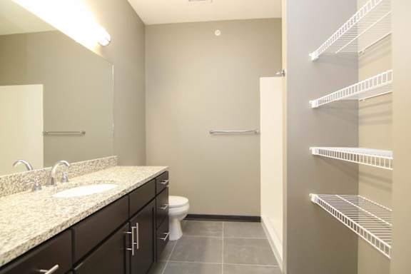 A bathroom with a sink, toilet, and shelves.