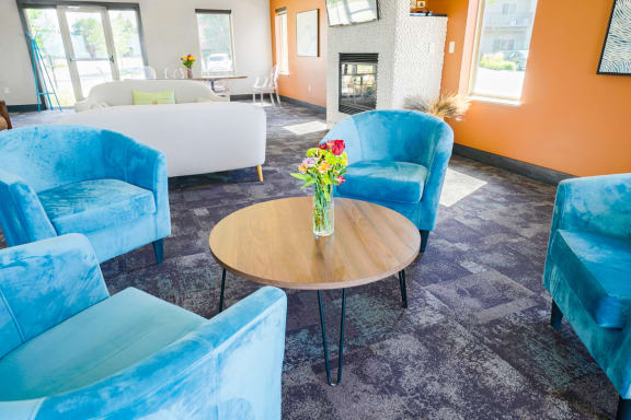 clubhouse with blue chairs and a table with a vase of flowers on it