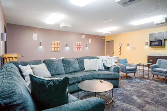 a theater room with a sectional couch and table seating in the back