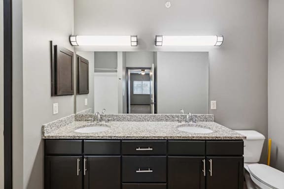 A bathroom with double sink granite vanity, an oversized mirror, and a medicine cabinet.