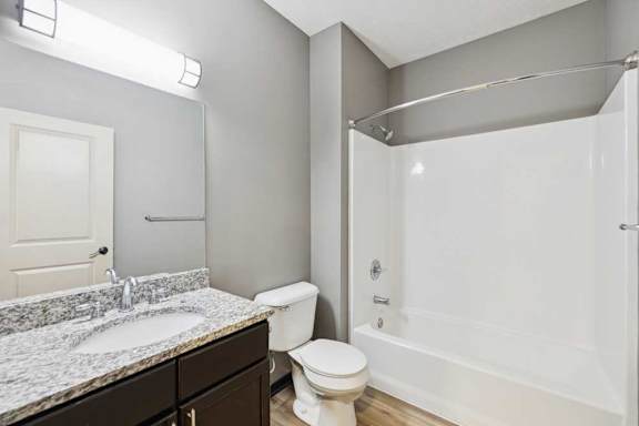 A bathroom with a granite vanity sink and a tub shower.