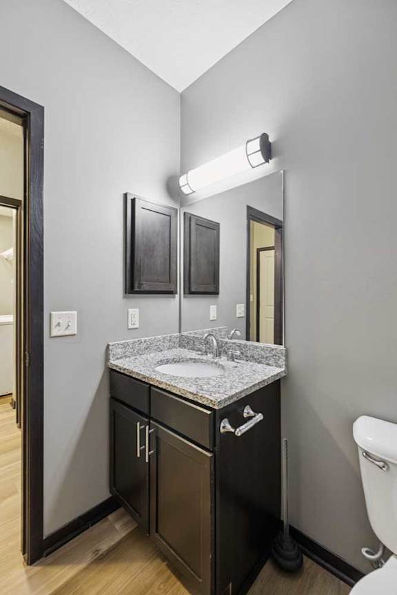 A bathroom with a granite vanity sink, an oversized mirror with overhead lighting, and a medicine cabinet.