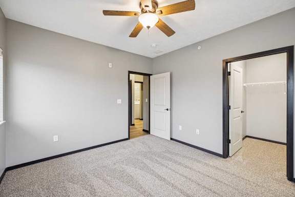 A carpeted bedroom with a ceiling fan and walk-in closet.