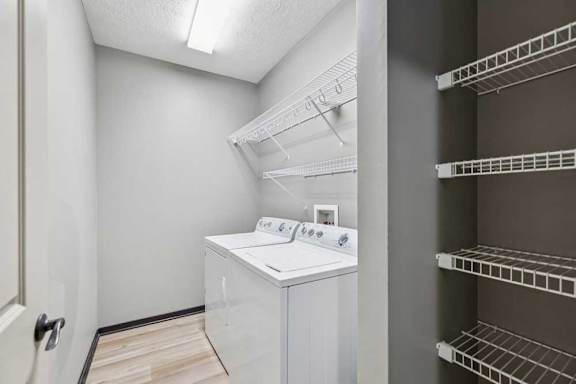 A laundry room with a full-sized washer and dryer, and overhead storage.